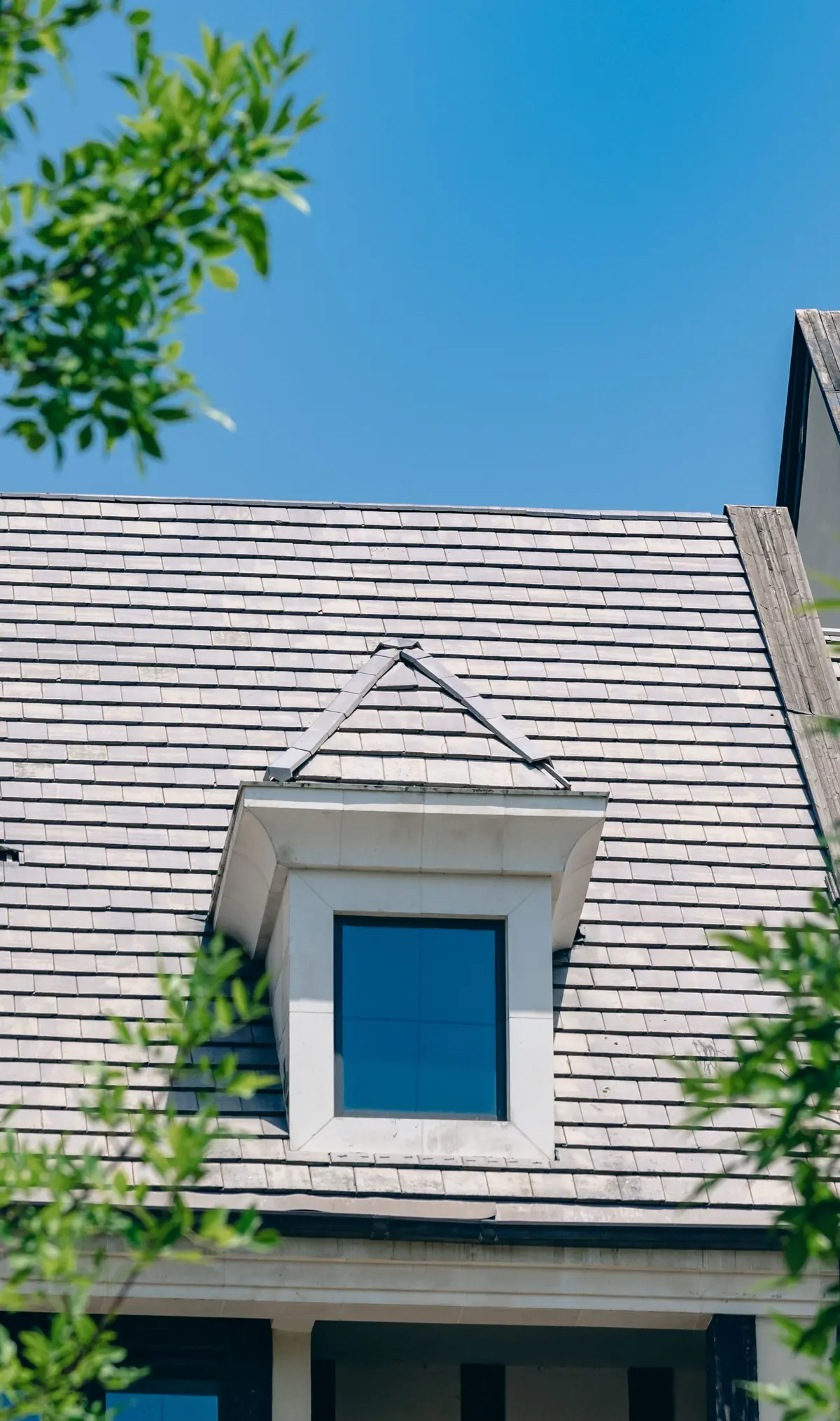 Architectural inspiration: white-trimmed dormer in a shingled roof beneath a clear blue sky