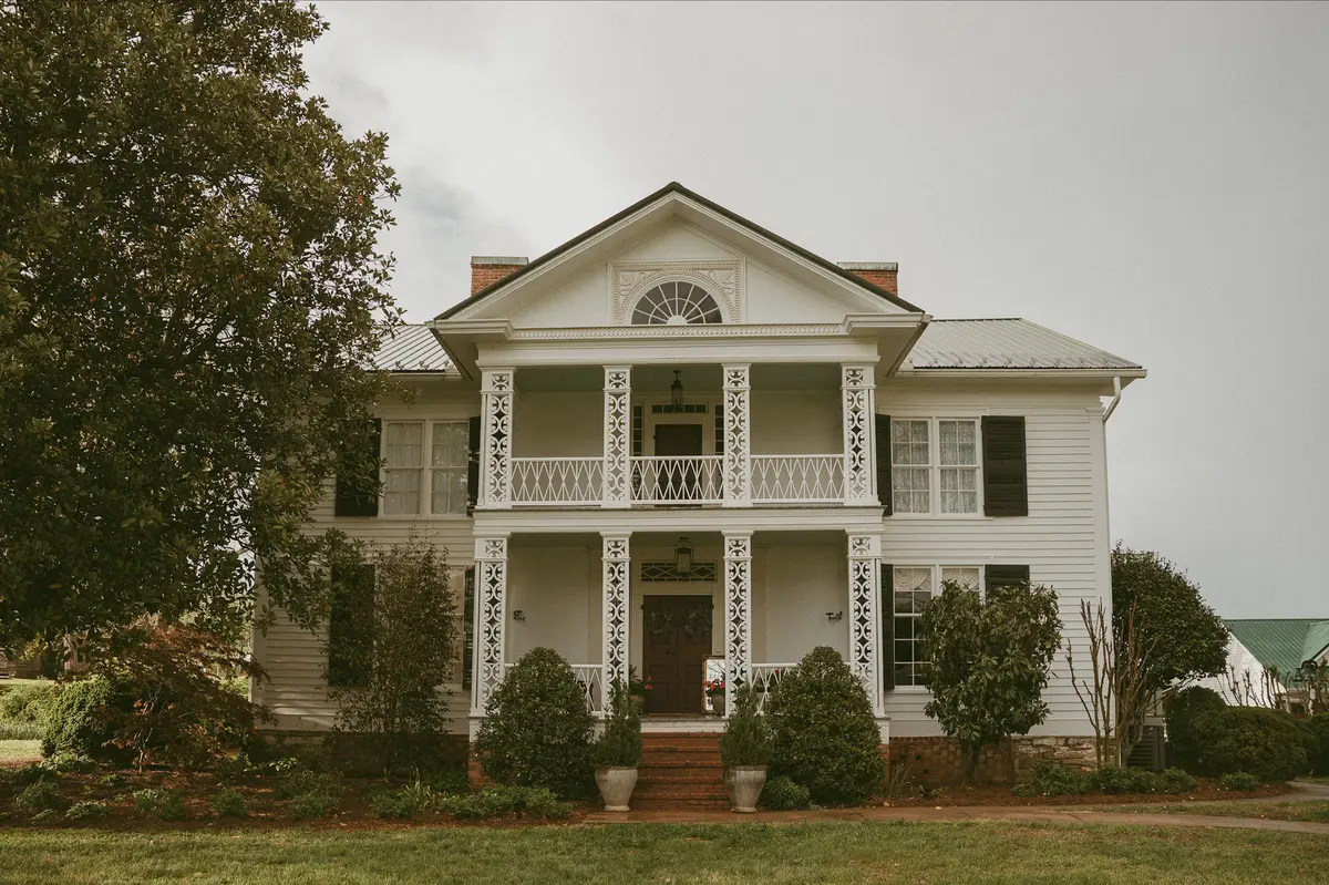 Architectural inspiration: traditional white house with an ornate two-story porch and surrounding trees